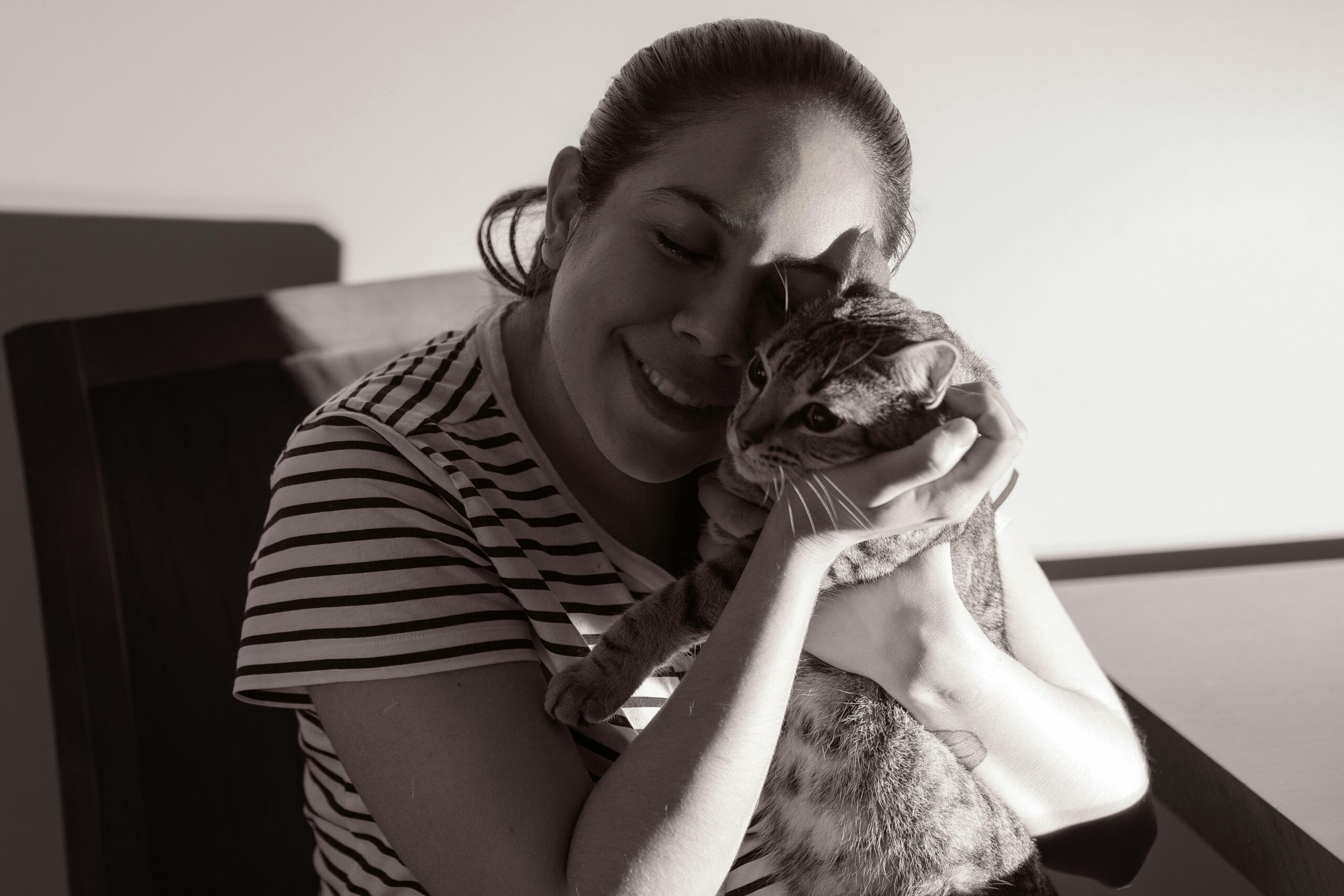 A woman lovingly embraces her cat, showcasing a tender moment indoors.